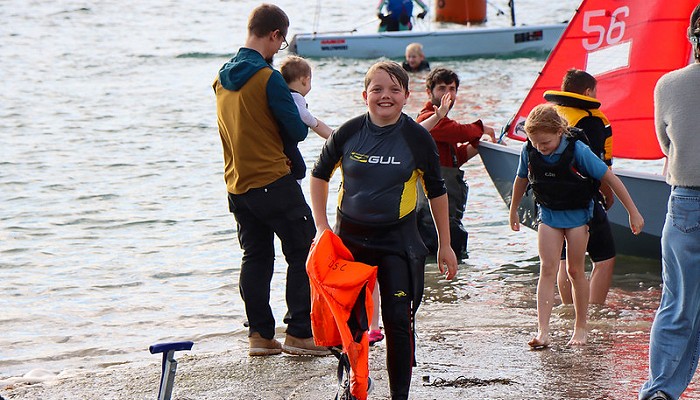 boy holding a life jacket walking out of the sea