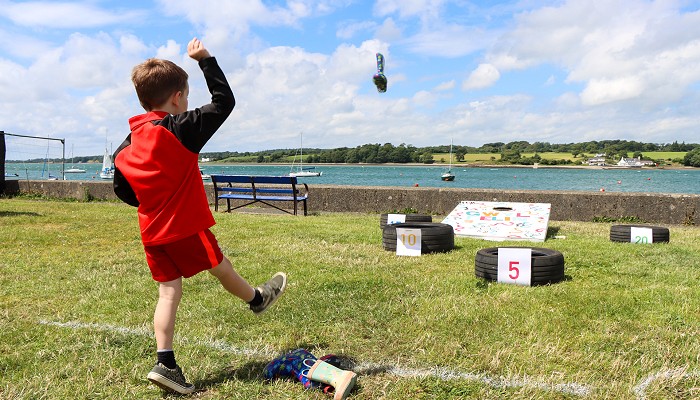 Child playing toss the welly by the waterfront.